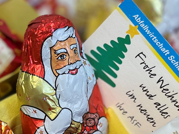 Schokoladenweihnachtsmann vor ein Karte mit der Aufschrift "Frohe Weihnachten"