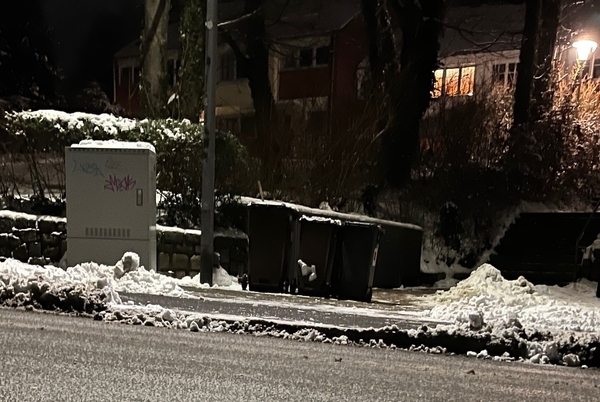 Im Winter am Straßenrand bereitgestellte Abfallbehälter. Damit die Tonnen problemlos zum Sammelfahrzeug gezogen werden können, wurde ein Durchbruch in den zwischen Tonnen und Straße liegenden Schneewall geschaufelt.  